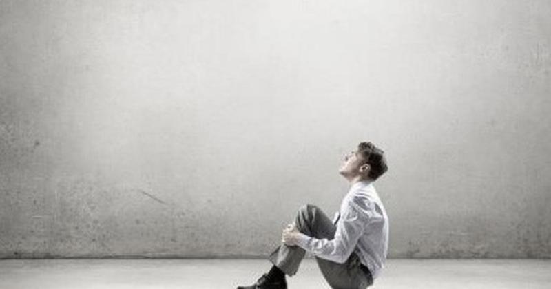 Hình ảnh một người phụ nữ ngồi một mình trong một căn phòng rộng lớn, thể hiện sự cô đơn và trống trải