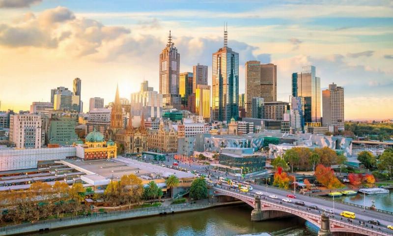 Hình ảnh một lễ hội ngoài trời ở Melbourne với người dân mặc trang phục đa dạng, có thể thấy dấu hiệu của thời tiết thay đổi (dù, áo khoác)